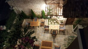 An outdoor patio with stone flooring, wooden furniture, and a brick wall.