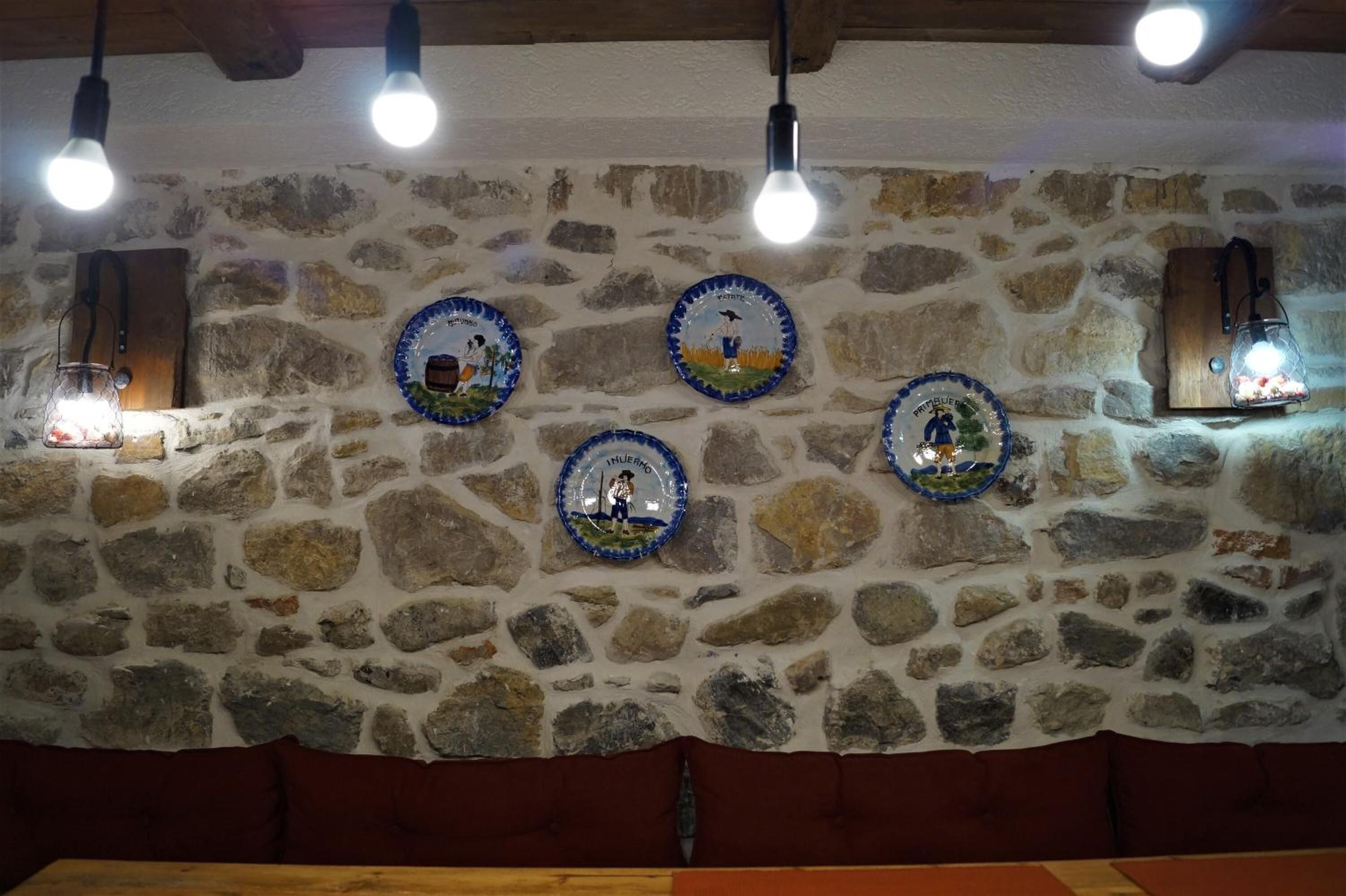 A stone wall with four ceramic plates, each depicting a different scene.