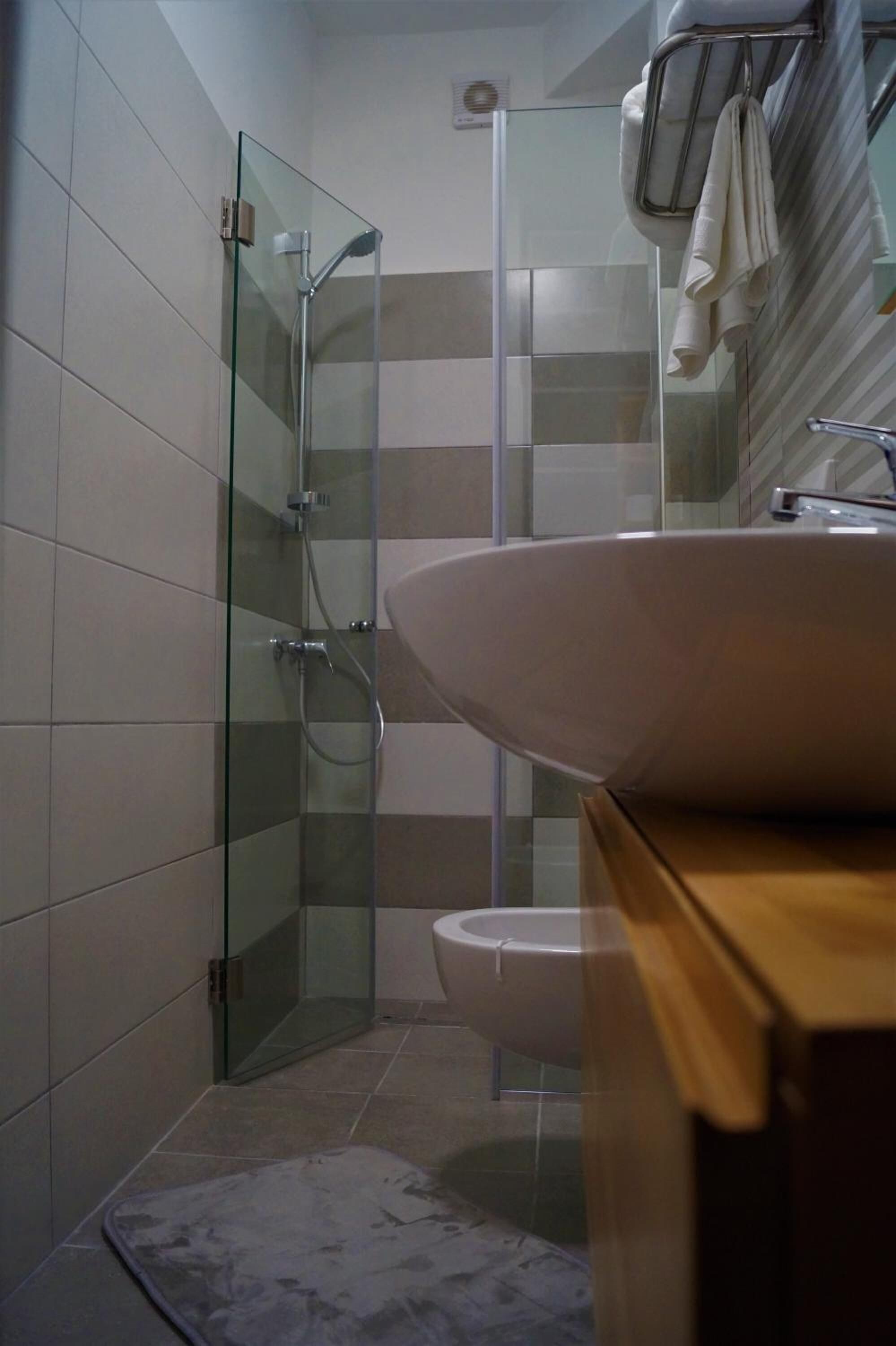 Un baño moderno con cabina de ducha de vidrio, un lavamanos blanco y un perchero para toallas.