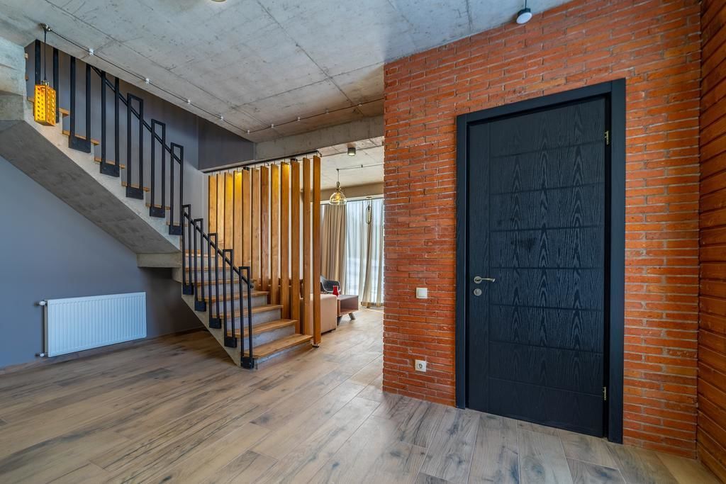 A modern interior with a staircase, a black door, and a brick wall.