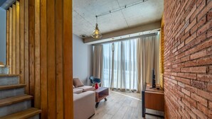 Una sala de estar moderna con una escalera, un sofá, una mesa de centro y un televisor sobre un soporte de madera.