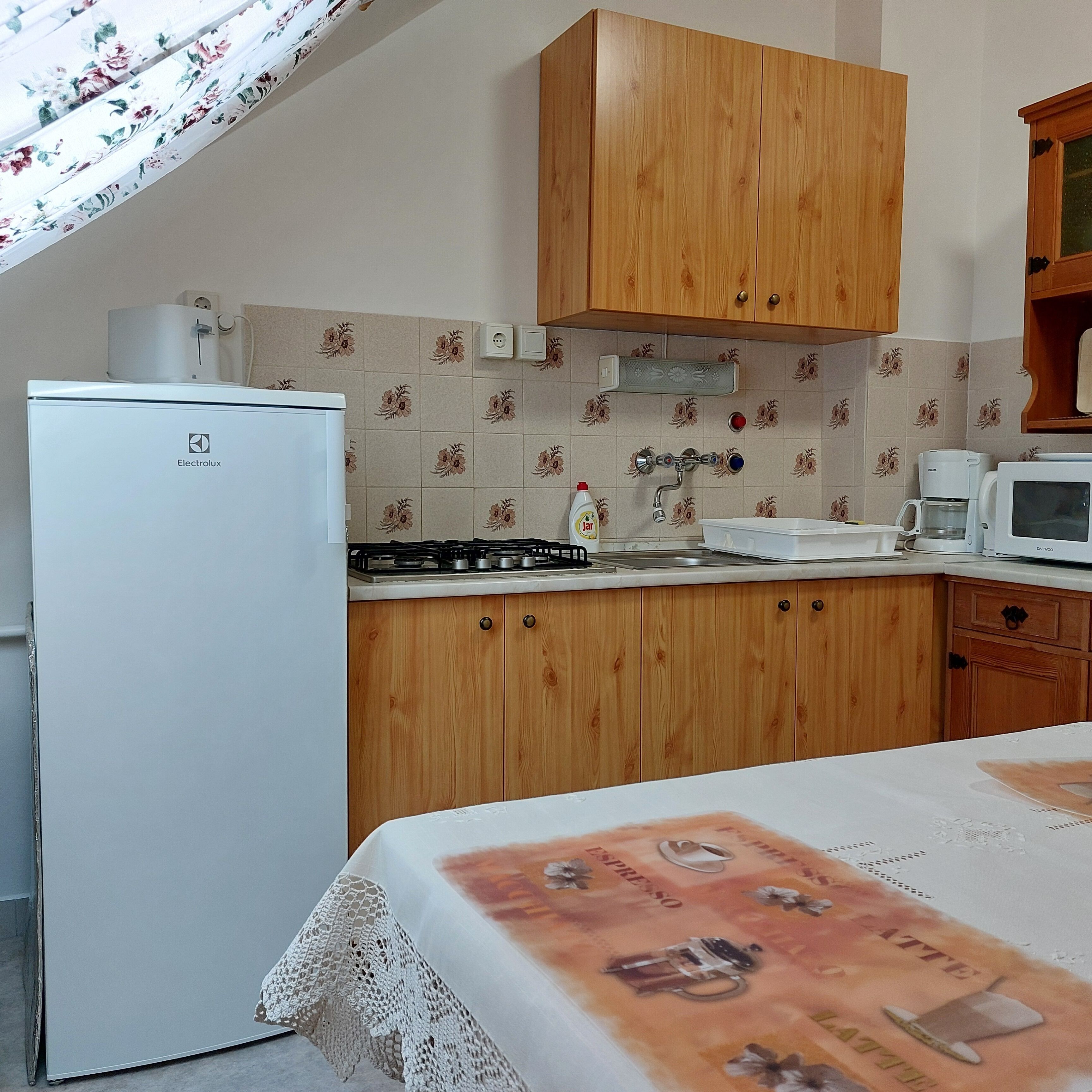 Una cocina compacta con armarios de madera, un refrigerador, una estufa y un microondas.