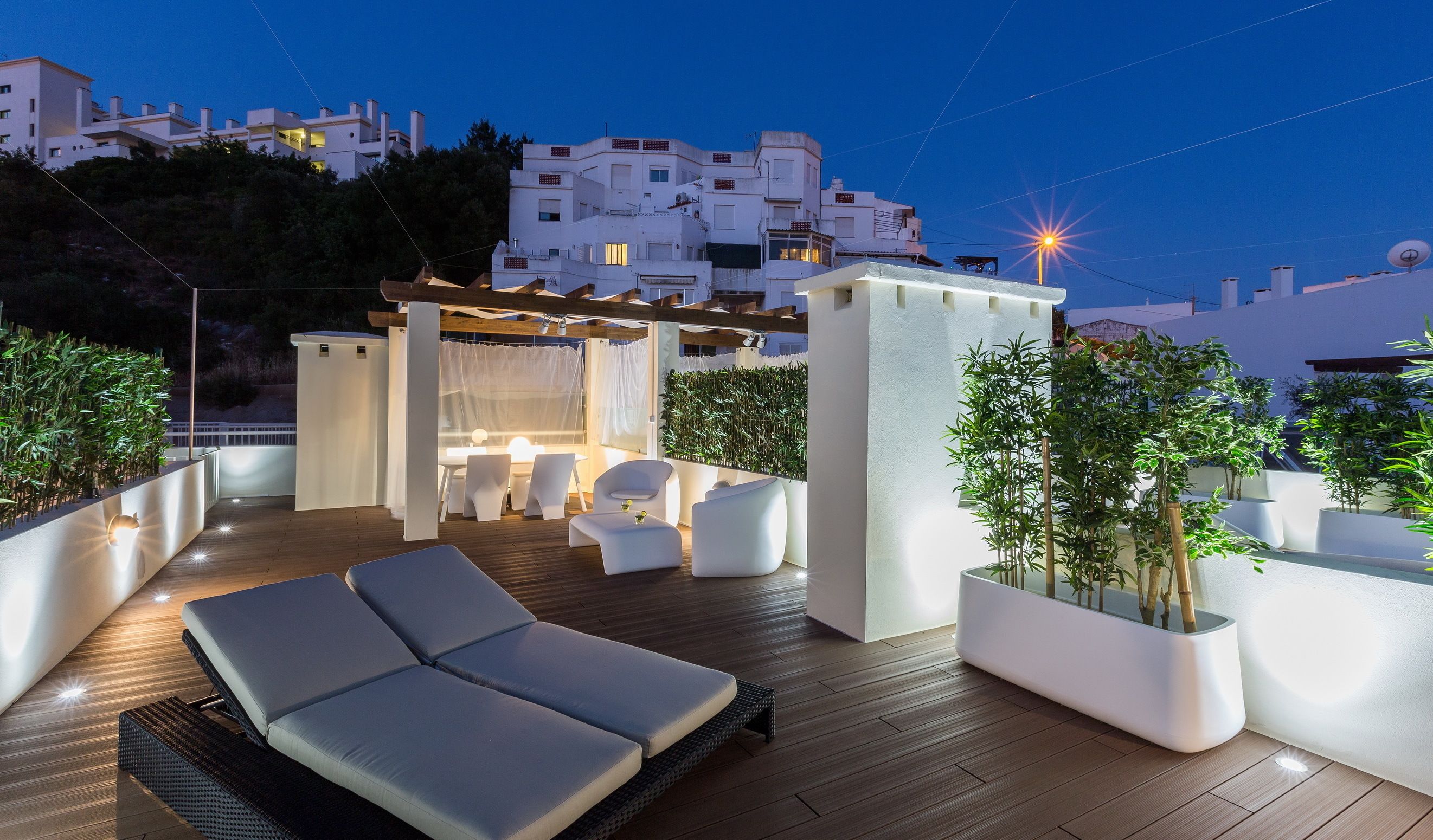 An outdoor terrace with a lounge area, seating, and a view of the cityscape at dusk.