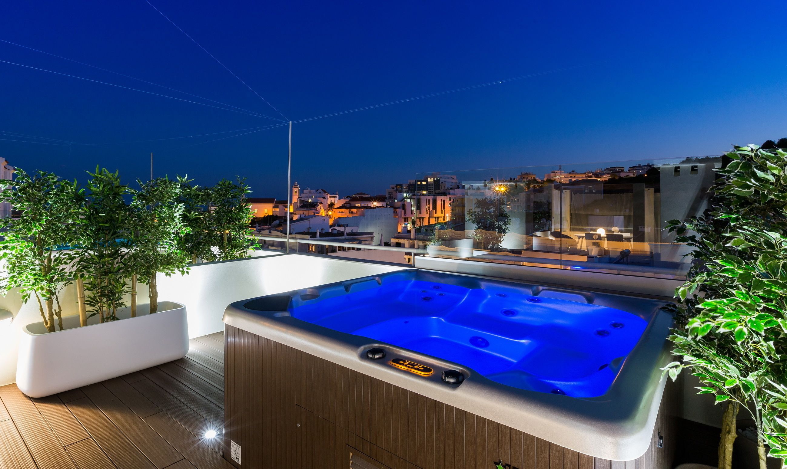Une terrasse sur le toit avec un jacuzzi, des plantes en pot et une vue sur la ville au crépuscule.