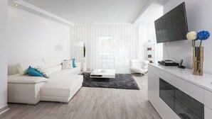 A modern living room with a white sofa, a coffee table, a TV, and a fireplace. - D Loft Downtown (Albufeira)