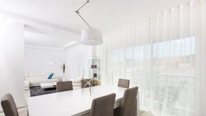 A modern living room with a white sofa, a coffee table, and a dining area with a white table and four chairs. - D Loft Downtown (Albufeira)