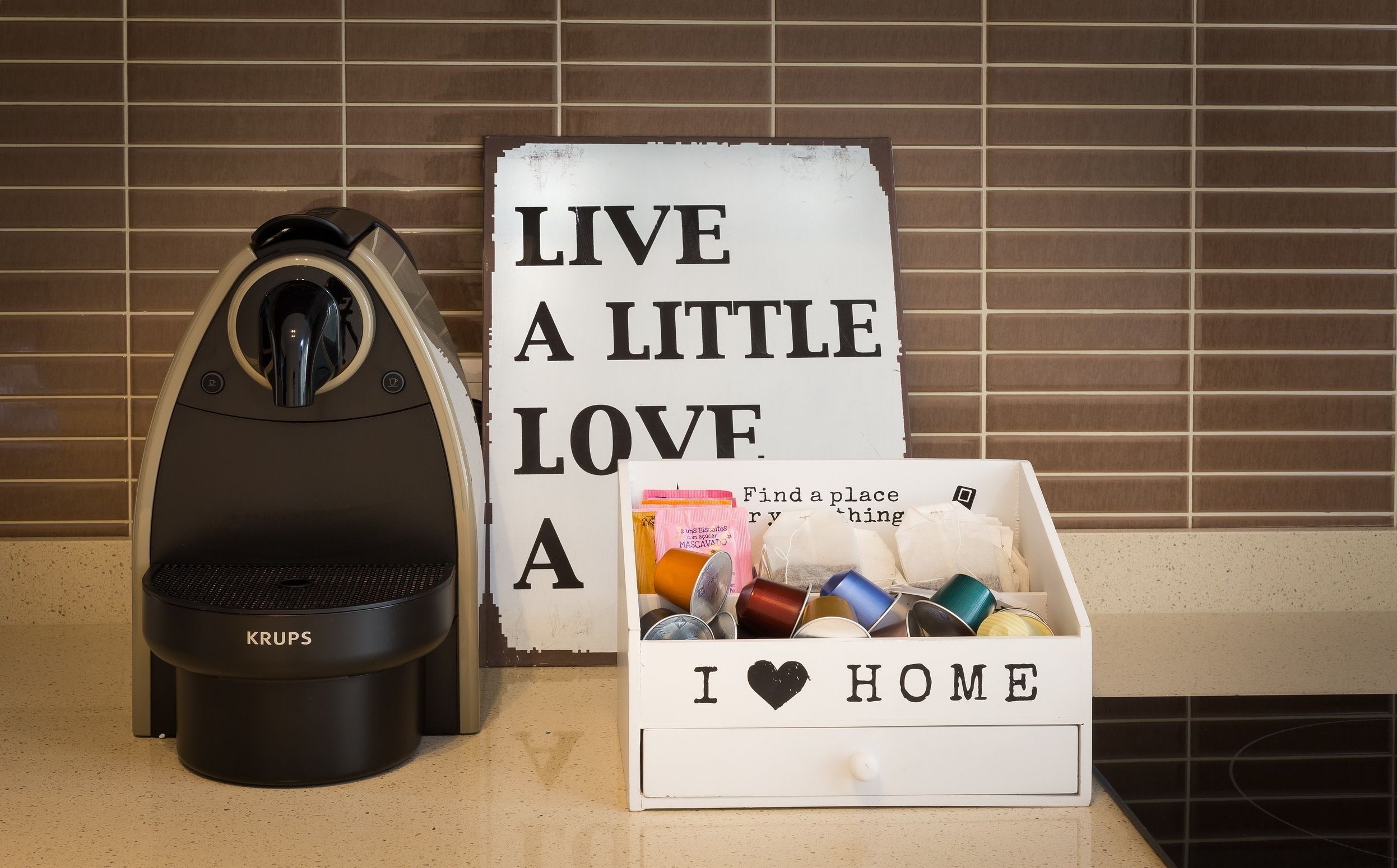 A coffee maker, a sign with the text "LIVE A LITTLE LOVE A", and a box with the text "I ♥ HOME".