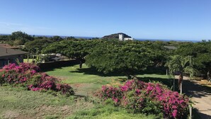 A residential area with a view of the ocean, surrounded by lush greenery and flowering bushes. - 5 Bedroom, 6 Bath Home with Private Pool -  Ocean & Mountain Views (Waianae)