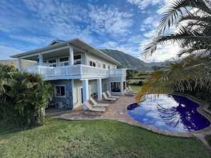Une maison à deux étages avec un balcon, une piscine et une vue sur les montagnes.