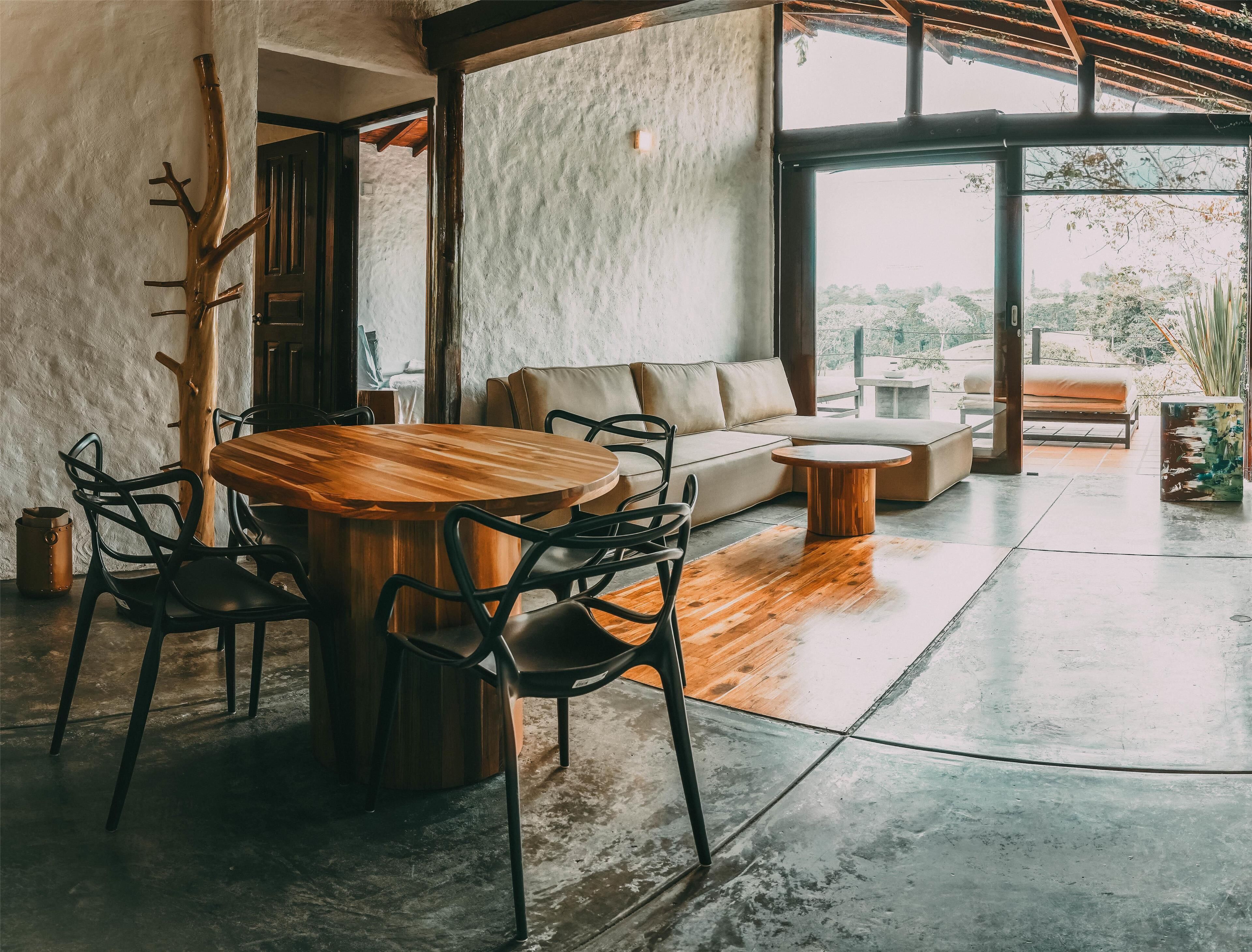 A spacious room with a wooden dining table, black chairs, a sofa, and a coffee table.