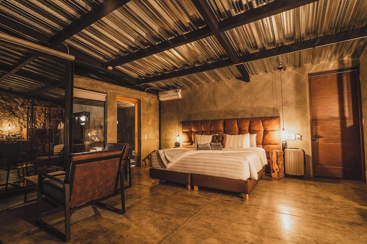 A spacious bedroom with a large bed, a wooden headboard, and a rustic ceiling.
