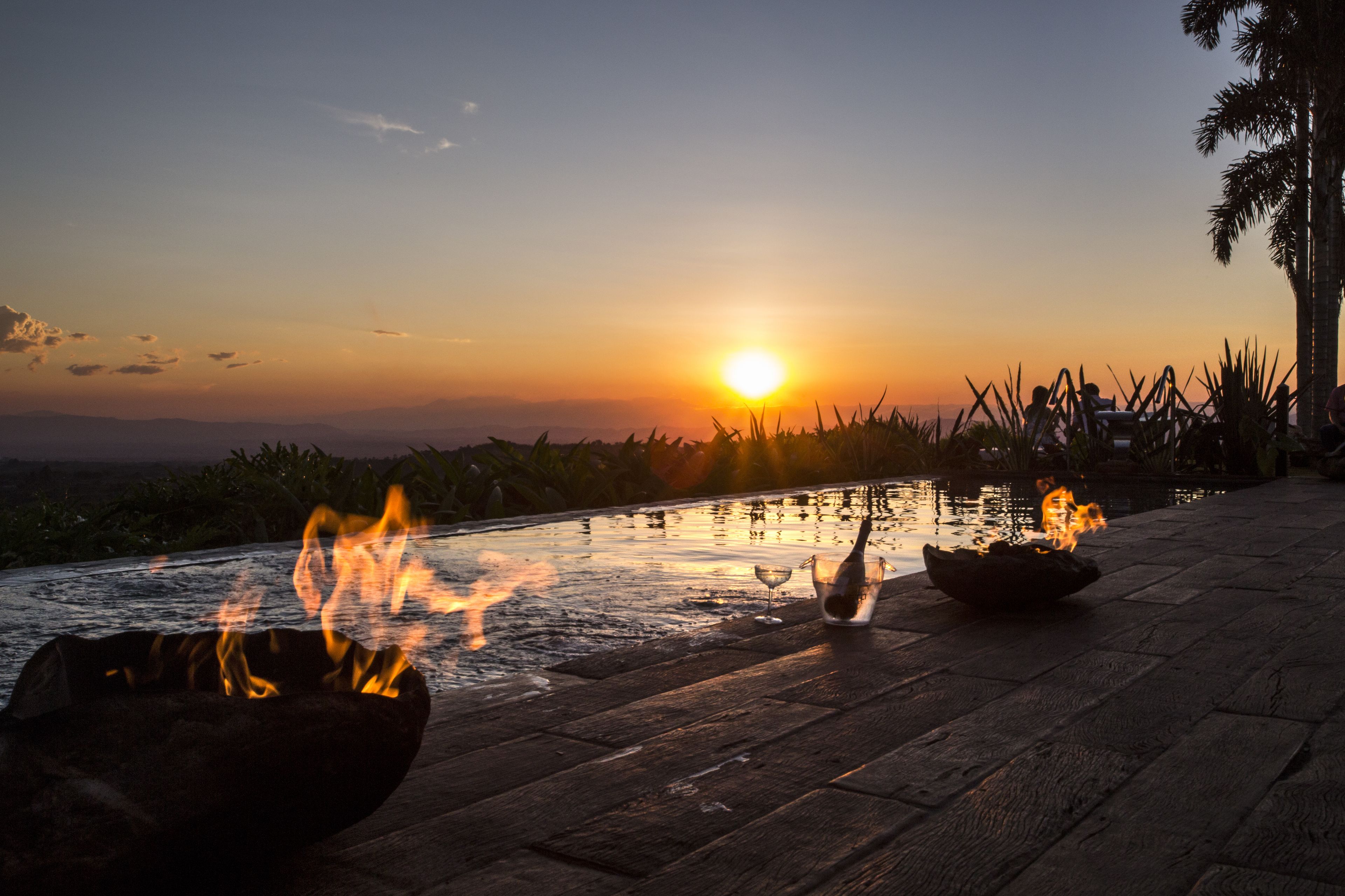 A sunset view with a fire pit and a glass of wine on a wooden deck.