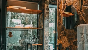 A modern bathroom with a stone wall, wooden ceiling, and a large window. - Bio Habitat Hotel, AKEN SOUL Collection (Circasia)