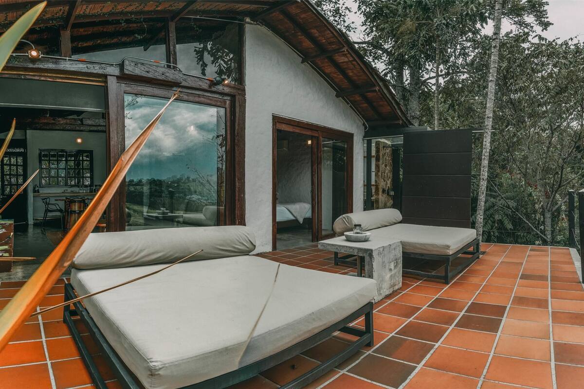 A modern outdoor living area with a sofa and a small table, surrounded by a tiled patio.