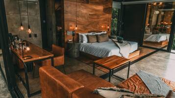 A modern, well-lit room with a wooden headboard bed, a wooden dining table, and a leather sofa.