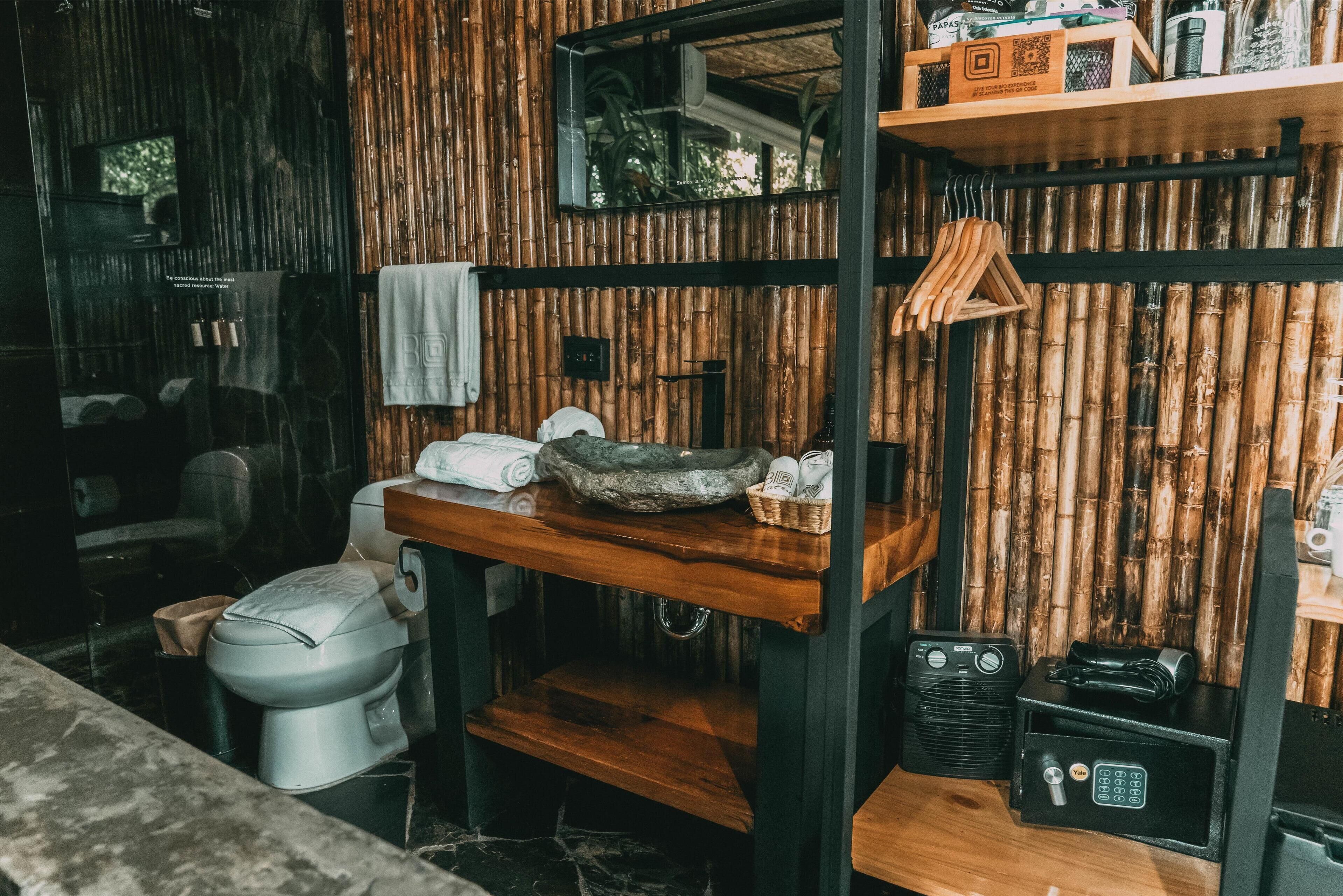 A bathroom with a bamboo wall, a wooden vanity, a toilet, and a radio.