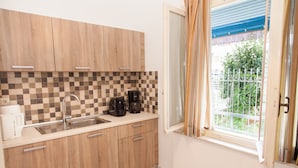 A kitchen with wooden cabinets, a checkered backsplash, a sink, and a window with curtains. - Fabulous Apartment Across Flisvos (Palaio Faliro)