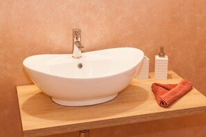 A white oval sink with a modern faucet on a wooden countertop. - Fabulous Apartment Across Flisvos (Palaio Faliro)