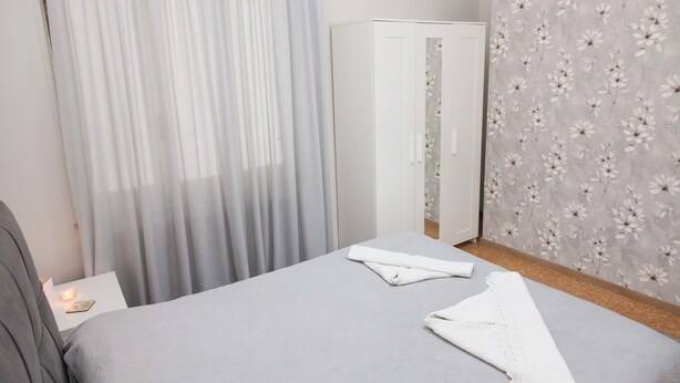 A bedroom with a bed, a wardrobe, and a floral wallpaper. - Fabulous Apartment Across Flisvos (Palaio Faliro)
