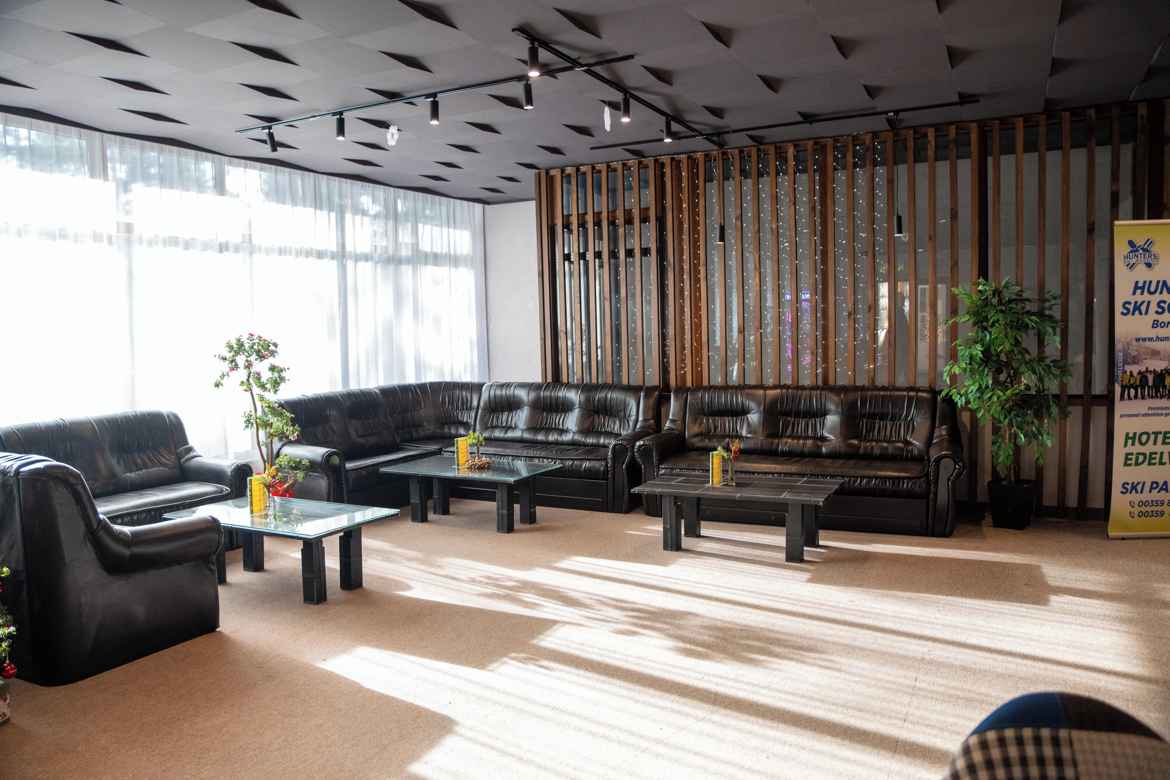 A modern hotel lobby with leather sofas, glass coffee tables, and a large window.