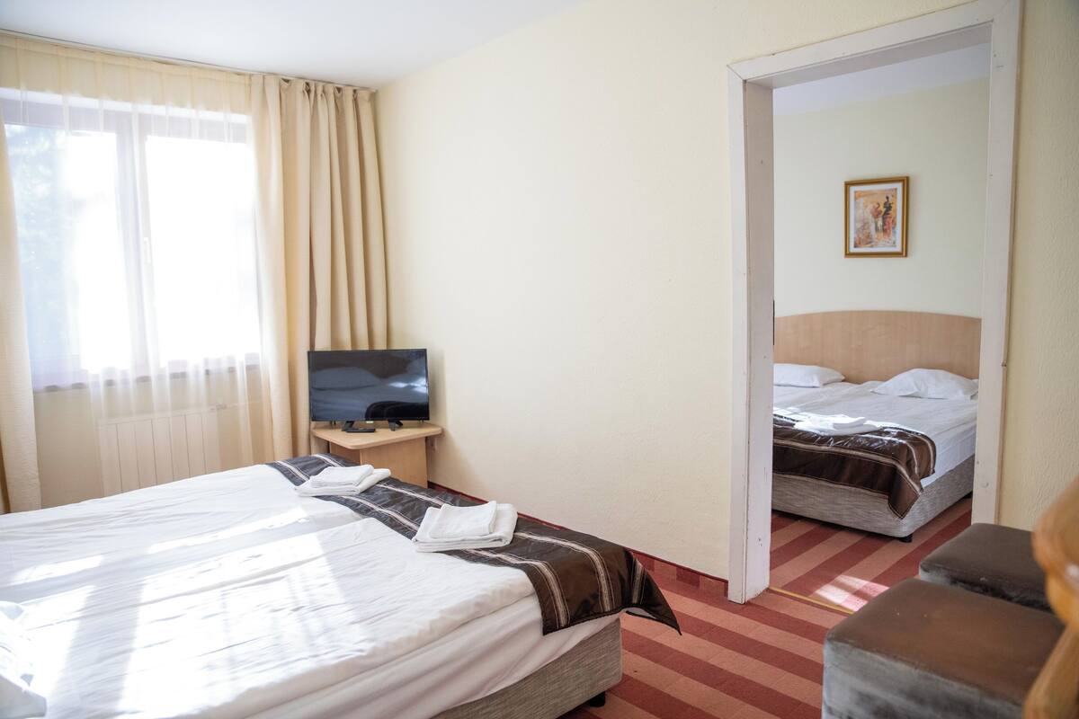 A hotel room with two beds, a TV, and a painting on the wall.