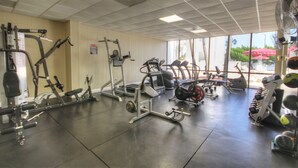 A gym with various exercise equipment, large windows, and a view of the outdoors.