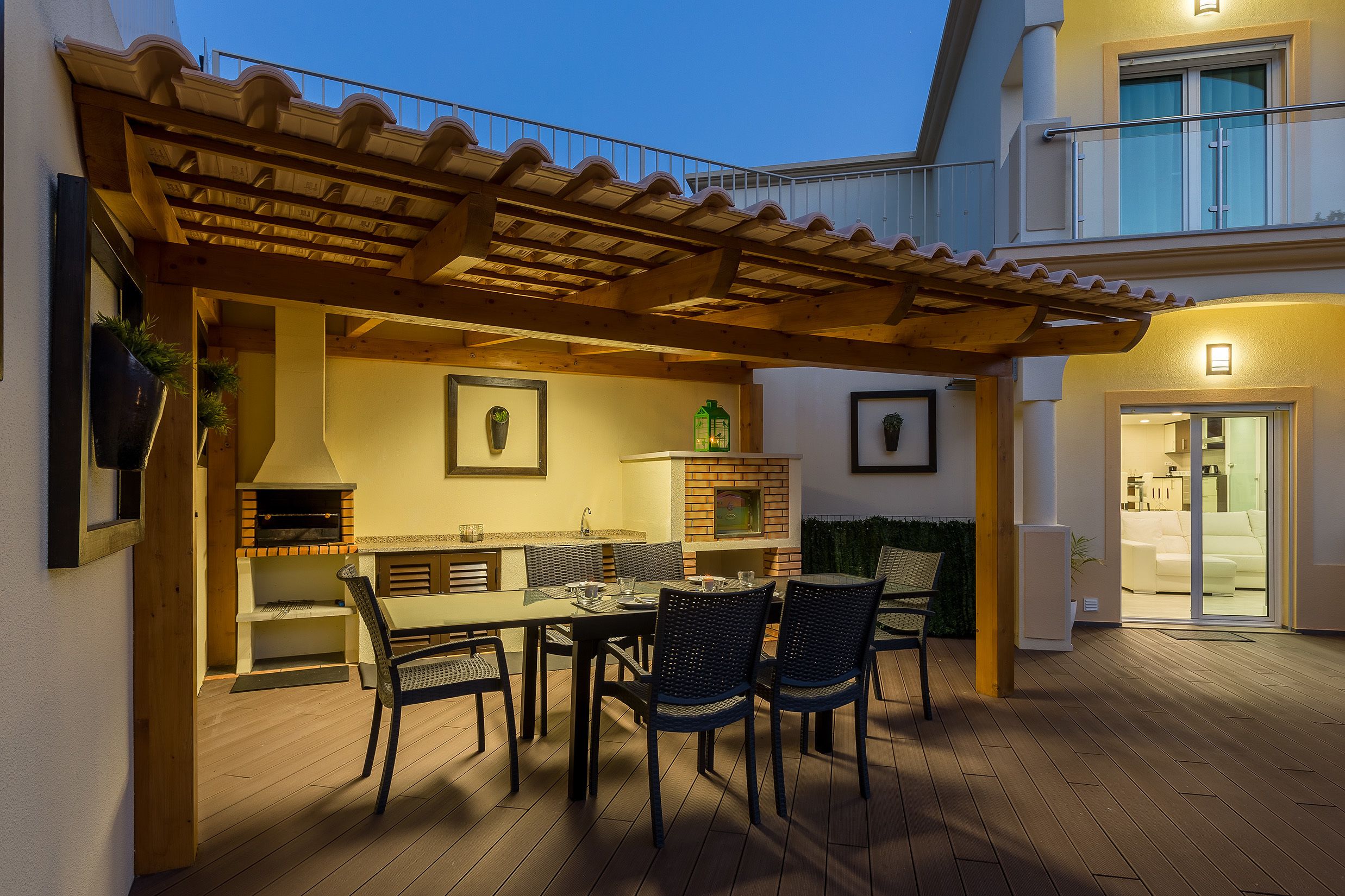 Eine Terrasse im Freien mit einer Pergola, einem Esstisch, Stühlen und einem Backofen aus Ziegeln.