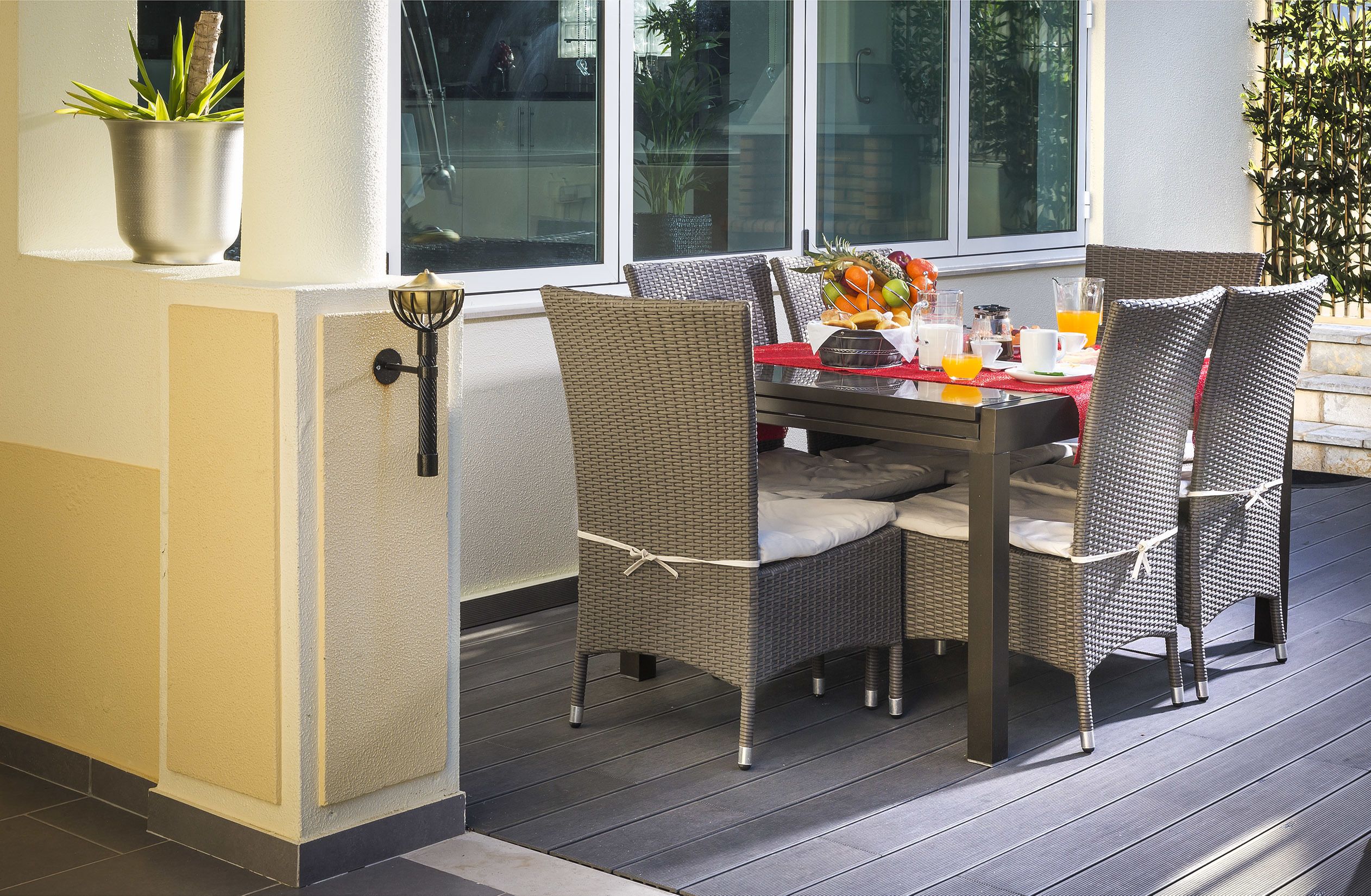 A dining area with wicker chairs and a table set for breakfast.