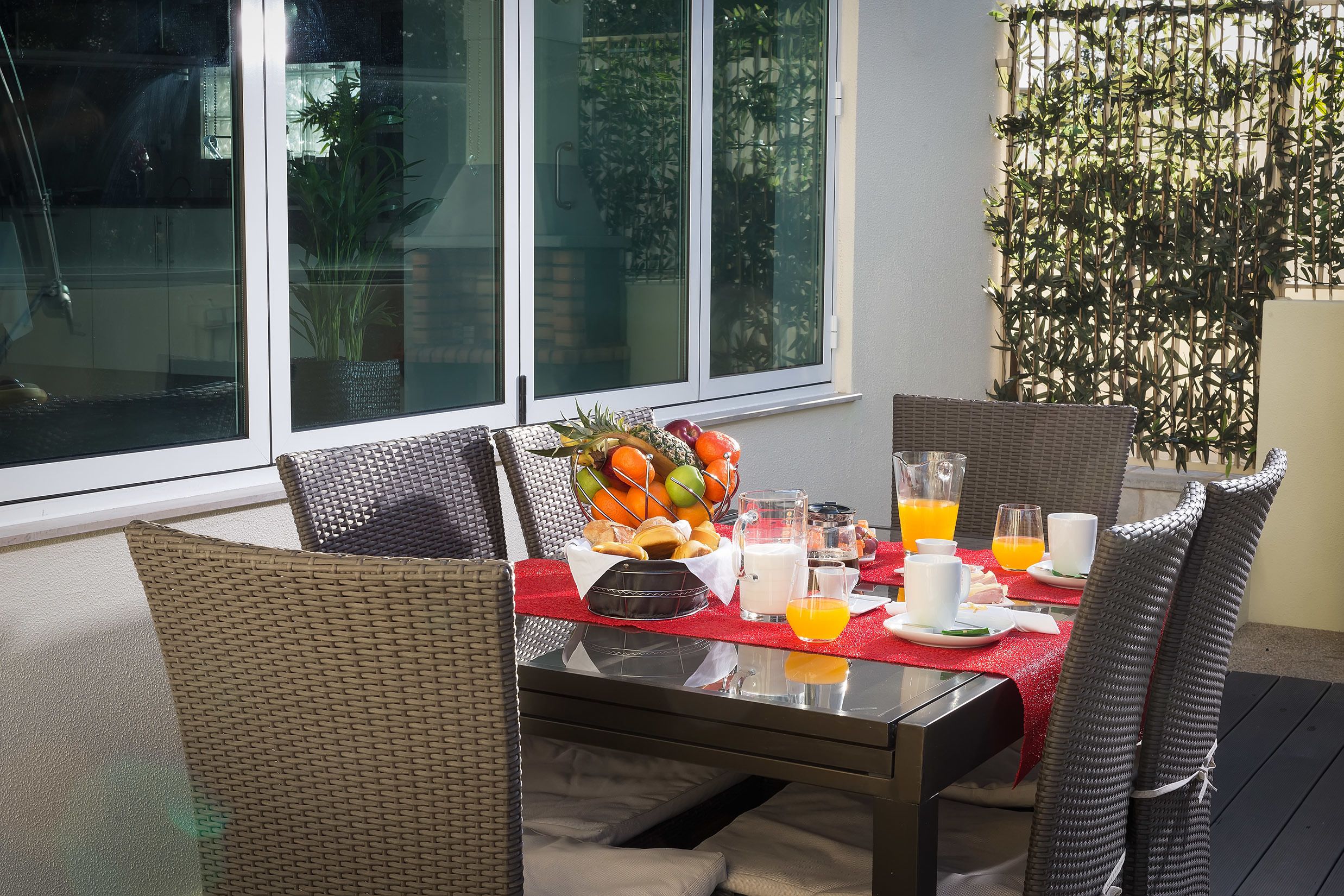 Une table à manger dressée avec des aliments pour le petit-déjeuner, notamment des fruits, des boissons et des assiettes.
