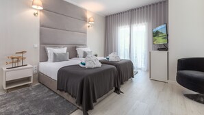Una habitación de hotel moderna con dos camas, un televisor de pantalla plana, un escritorio pequeño y una silla.