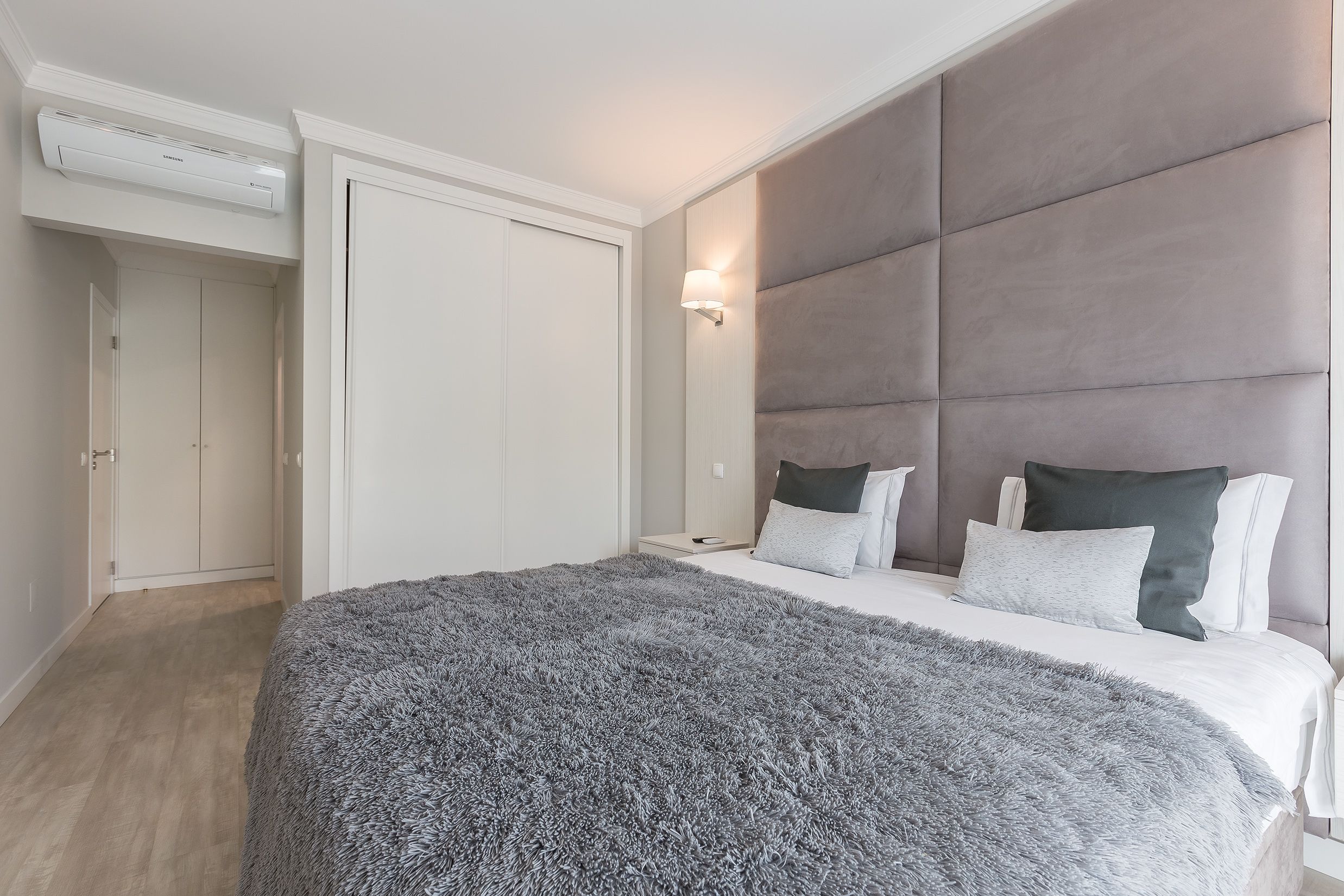 Une chambre à coucher avec un grand lit, une armoire, une table de chevet et une lampe fixée au mur.