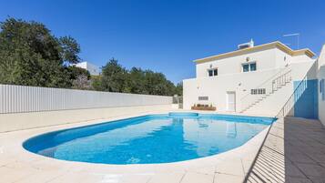 Una piscina al aire libre, sillones reclinables de piscina