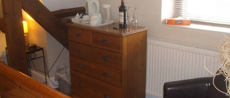 A bedroom with a wooden dresser, a bed, a radiator, and a window with blinds.