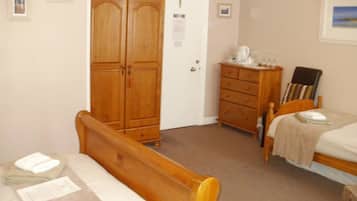 Een slaapkamer met een houten bed, een kledingkast van hout, een dressoir en een klein tafeltje met een stoel.