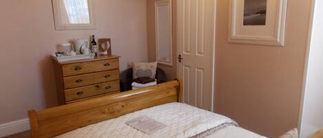 A bedroom with a bed, a dresser, a television mounted on the wall, and a door.