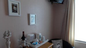 Habitació d'hotel amb un taulell de fusta, una televisió penjada a la paret i una finestra amb cortines.