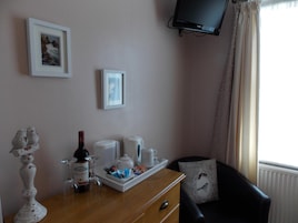 Habitación de hotel con tocador de madera, televisor montado en la pared y ventana con cortinas.