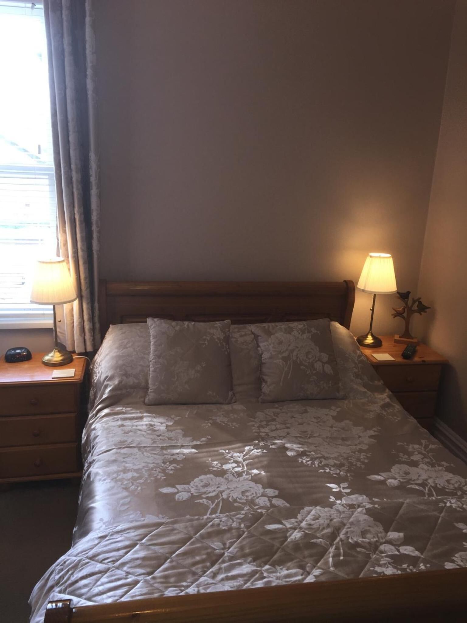 A neatly made bed with a floral bedspread, two bedside lamps, and a nightstand with a remote control.