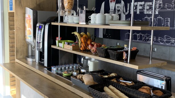 A breakfast bar with a coffee machine, cereal dispensers, fruit, and bread. - ibis budget Mantes-la-Jolie Sully (Mantes-la-Jolie)