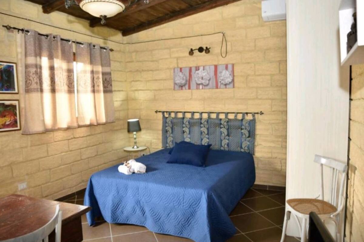 Ein Schlafzimmer mit einem Bett, einem Nachttisch, einem Sessel und einem Tisch.