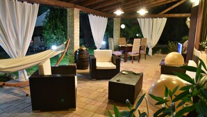 Un espace extérieur aménagé en terrasse, avec des meubles en osier, un hamac et un grand ballon.