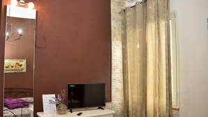 Une chambre à coucher avec un lit, une commode, une télévision, un miroir et un rideau de douche.