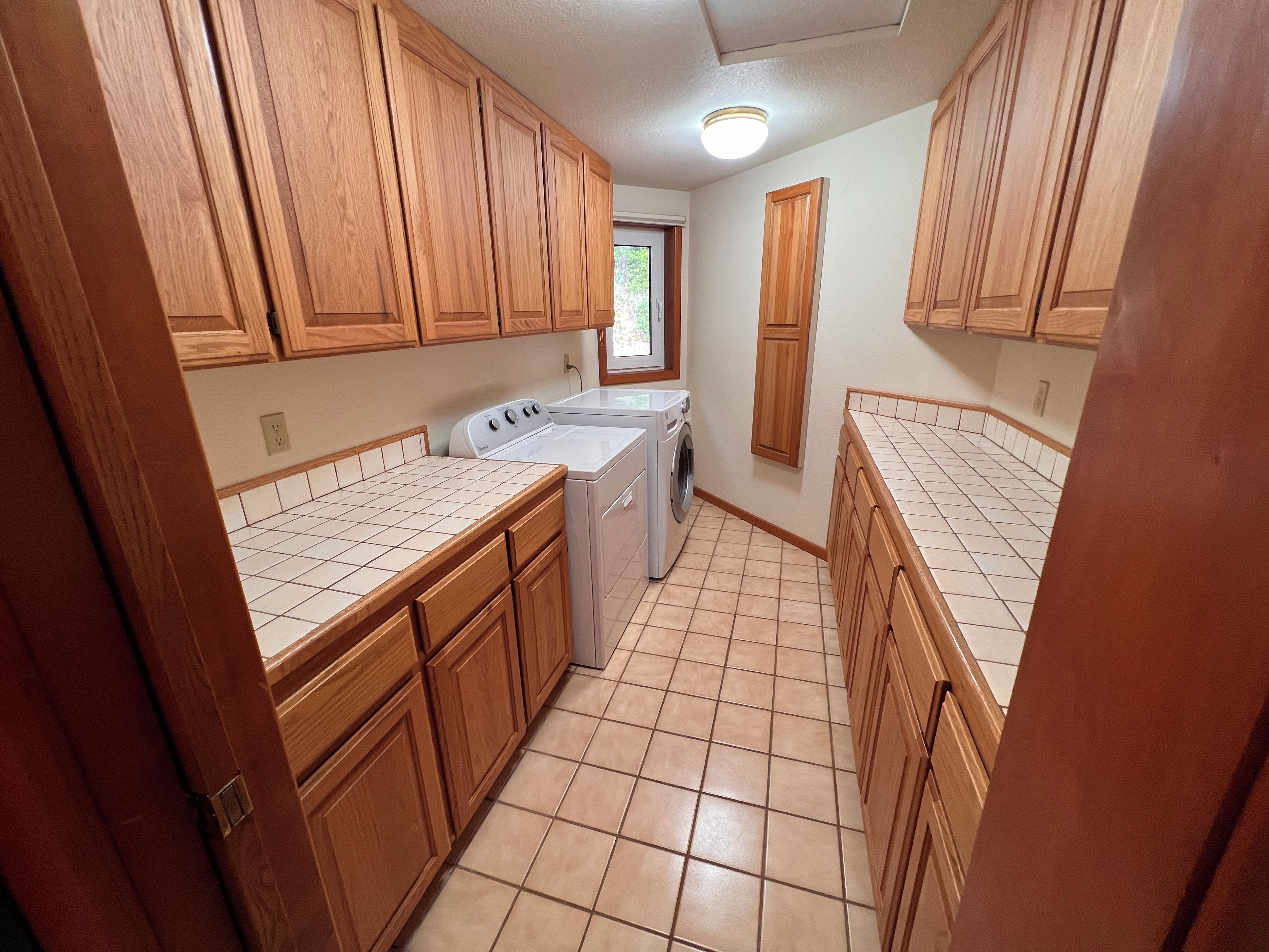 Una cocina compacta con armarios de madera, lavadora y piso de baldosas.