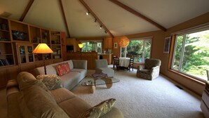 A cozy living room with a sofa, armchairs, a coffee table, and a dining area with chairs and a table. There is a bookshelf and a lamp. Large windows provide natural light and a view of greenery outside. - Battle Rock House-Port Orford - Spectacular Views
No Wind
Broadband Internet (Port Orford)