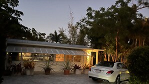 Une maison moderne dotée d’un patio couvert, d’une allée en gravier et d’une voiture garée.