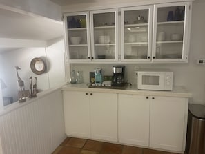A kitchen with white cabinets, a coffee maker, a microwave, and decorative items on the counter.