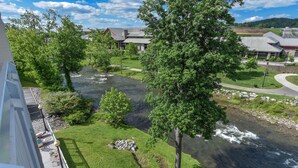 A river flowing through a green landscape with trees and buildings in the background.