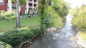 Une rivière traverse un espace aménagé, avec un bâtiment visible au loin.