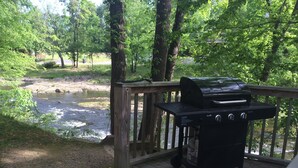 Une terrasse dotée d’un barbecue portable et offrant une vue sur une rivière.