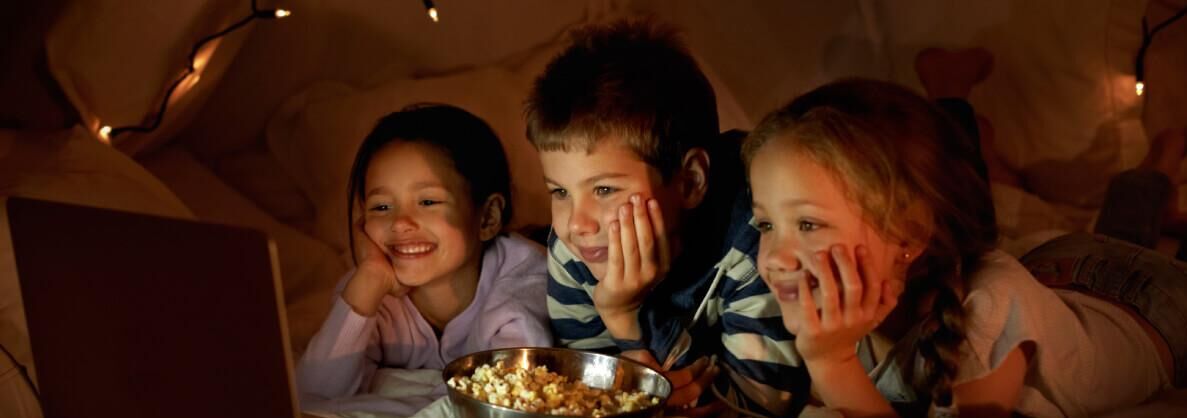 En gruppe mennesker sidder tæt sammen med en skål popcorn i forgrunden.